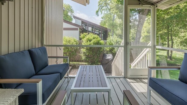 A covered outdoor area with a wooden deck, a blue sofa, and a table.