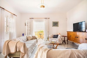 Quarto com duas camas, um sofá, uma TV e um armário de madeira.