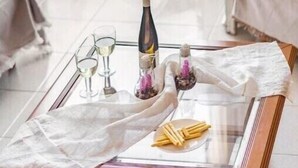A glass-top coffee table with a white cloth, a bottle, glasses, and a decorative item. - Apartment 'Villa Dorita' with Sea View, Wi-Fi and Air Conditioning (Corfu)