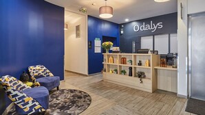 Un área de recepción con pared azul, un mostrador y un espacio de espera con sillas estampadas.