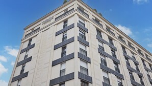 Un edificio de varios pisos con fachada plana, ventanas distribuidas uniformemente y una serie de balcones.