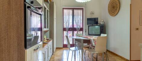 A kitchen with a dining area, a television, and a decorative wall piece.