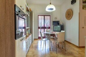 A kitchen with a dining area, a television, and a decorative wall piece. - Villa 'Torretta - Mare Salento' with Sea View, Private Garden and Air Conditioning (Torretta mare taranto)