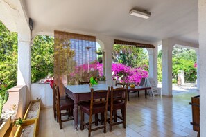 A covered patio with a table and chairs, surrounded by plants and flowers. - Villa 'Torretta - Mare Salento' with Sea View, Private Garden and Air Conditioning (Torretta mare taranto)