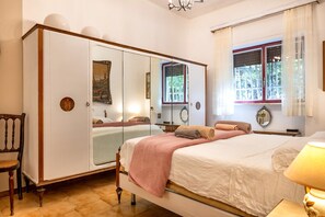 A bedroom with a bed, a wardrobe, a chair, and a window with curtains. - Villa 'Torretta - Mare Salento' with Sea View, Private Garden and Air Conditioning (Torretta mare taranto)