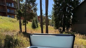 A hot tub with a bench in front, surrounded by trees and a building in the background. - 635 Wapiti, Hot tub, on FREE shuttle route (Fraser)