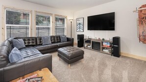 A living room with a sectional sofa, ottoman, TV, speakers, and a bookshelf. - 635 Wapiti, Hot tub, on FREE shuttle route (Fraser)