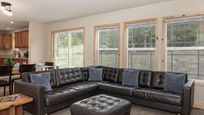 A living room with a sectional sofa, ottoman, and a dining area with a table and chairs. - 635 Wapiti, Hot tub, on FREE shuttle route (Fraser)
