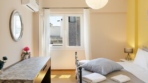 Et soveværelse med seng, natbord, spejl, vindue og en lampe.