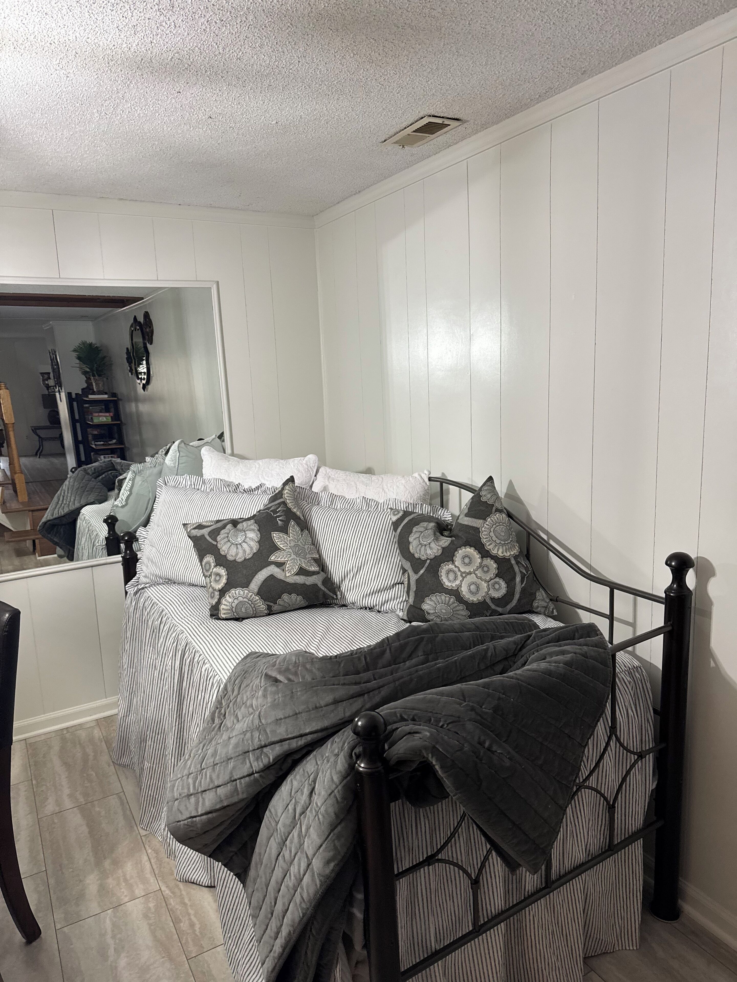 Una camera da letto con un letto, una sedia, un termosifone e uno specchio a parete.