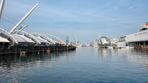 Un port de plaisance avec des bateaux, un grand voilier et un bâtiment moderne surmonté d’un dôme.