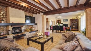 Una sala de estar con chimenea, sofá, mesa de centro y comedor con sillas.