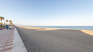 A beach with a paved walkway, palm trees, and the ocean. - Apartment 'Las Buganvillas' with Shared Pool, Private Terrace and Air Conditioning (Roquetas de Mar)
