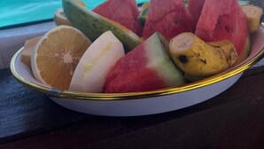 A plate of fruit on a table with a view of turquoise water and a distant island. - 1 Bedroom Apartment in Zanzibar (Zanzibar)