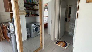 A spacious room with a large mirror, a washing machine, and a kitchen area with cabinets and a refrigerator. - 1 Bedroom Apartment in Zanzibar (Zanzibar)