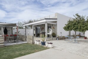 A modern house with a patio, outdoor seating, and potted plants.