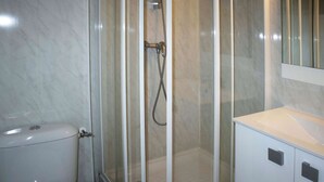 Une salle de bain avec une douche à parois de verre, des toilettes et un meuble avec un miroir au-dessus.