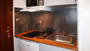 Une cuisine de taille réduite équipée d’un four à micro-ondes, d’un évier et d’un réfrigérateur compact.