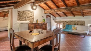 Un interior rústico con una mesa de madera, pared de piedra y un sofá con cojines.
