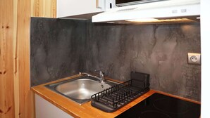 Una cucina compatta con un piano di lavoro in legno, un lavandino in acciaio inossidabile e un piano cottura a induzione nero.