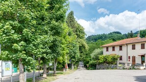 A quiet street with trees, a building with a red roof, and a clear sky. - Depandance Resort Apartment with Private Garden, Balcony, and Wi-Fi (Borgo San Lorenzo)