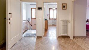 A hallway with a herringbone floor, a radiator, a door with a handle, and a staircase leading to another room. - Depandance Resort Apartment with Private Garden, Balcony, and Wi-Fi (Borgo San Lorenzo)