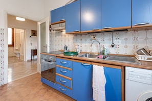 A kitchen with blue cabinets, a dishwasher, and a tiled backsplash.