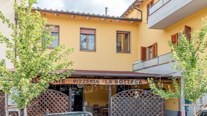 A yellow building with a sign reading 'PIZZERIA LA BOTTIGA.' - Depandance Resort Apartment with Private Garden, Balcony, and Wi-Fi (Borgo San Lorenzo)