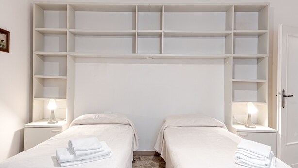 A room with two beds, a built-in shelving unit, and bedside lamps. - Depandance Resort Apartment with Private Garden, Balcony, and Wi-Fi (Borgo San Lorenzo)