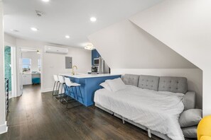 Een moderne loft slaapkamer met een groot bed, een kitchenette en een eethoek.