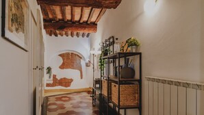 A hallway with a hexagonal patterned floor, a rustic brick wall, a wooden ceiling, and a shelf with baskets and a vase. - Castellare Degli Ugurgieri Central Apt in Siena (Siena)