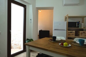 A kitchen with a refrigerator, microwave, and wooden shelves.