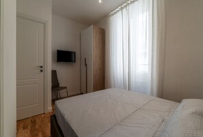Une chambre à coucher avec un lit, un téléviseur fixé au mur et une armoire.