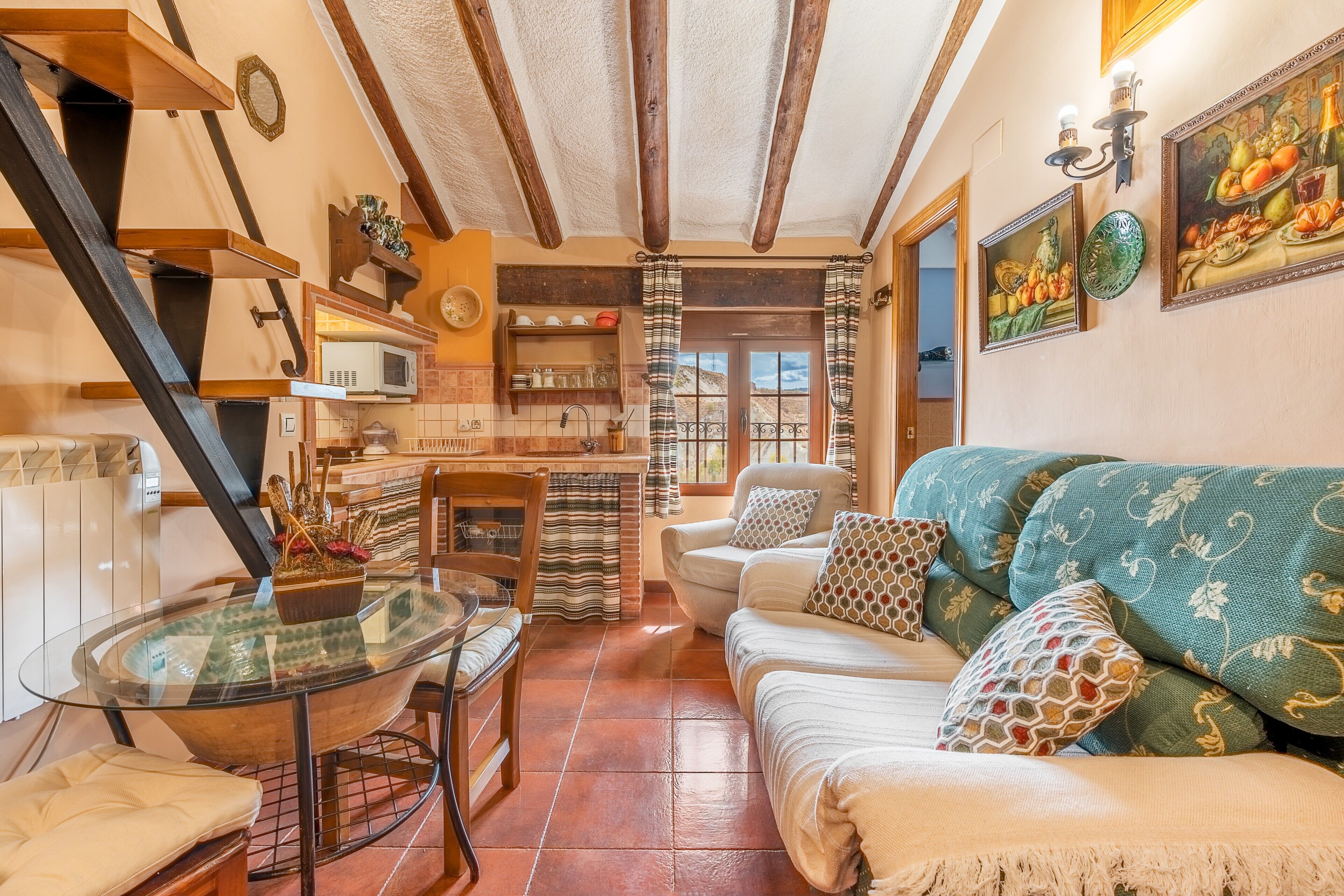 A cozy living room with a sofa, a glass table, and a kitchen area in the background.