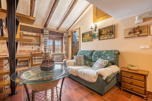 A cozy living room with a glass-top coffee table, a sofa with patterned cushions, a wooden side table, and a wall-mounted picture. - Apartment 'Tomillo' with Mountain View, Wi-Fi and Air Conditioning (Hinojares)