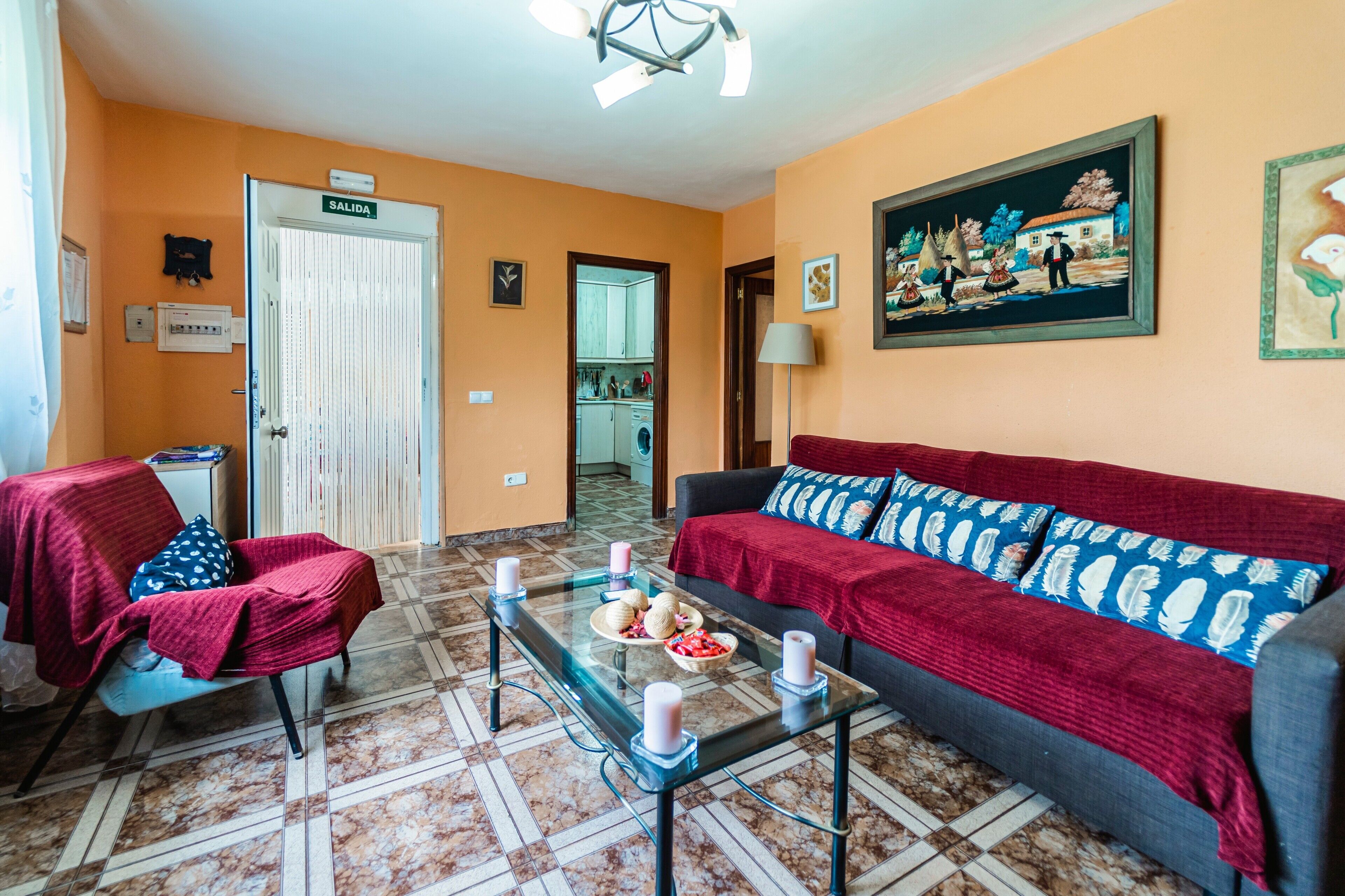 Una sala de estar con sofá, sillón, mesa de centro y una puerta con la leyenda 'SALIDA'.