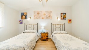 Une chambre avec deux lits, une table de chevet, des œuvres d’art murales et un lustre.