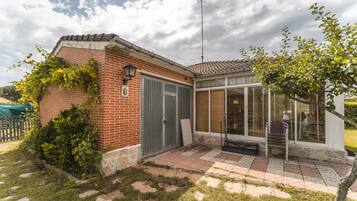 Una casa de ladrillo con un porche cubierto, una reja de metal y un pequeño jardín.