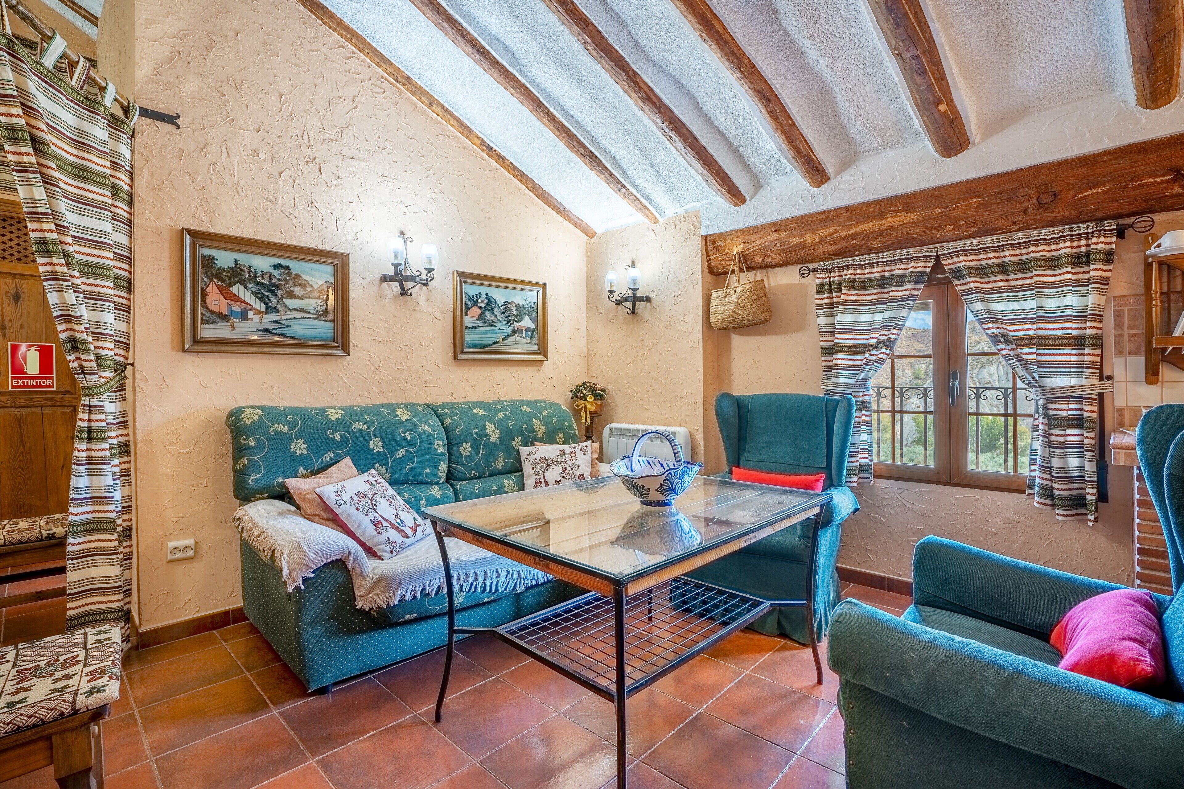 Ein gemütliches Zimmer mit Holzboden, einer Couch, einem Sessel und einem Tisch.