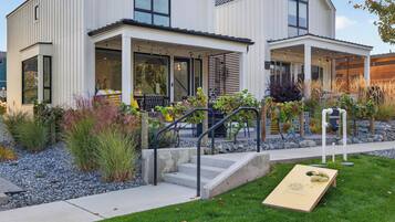 A modern two-story house with a covered porch, outdoor seating, and a well-maintained garden.