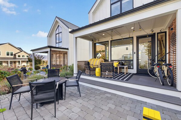 Une maison moderne dotée d’un patio couvert, aménagé avec du mobilier d’extérieur et un vélo.