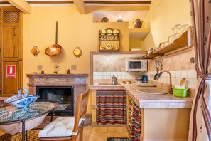 Eine Küche mit Kamin, Spüle und verschiedenen Küchenutensilien.