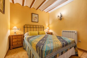 Ein Schlafzimmer mit Bett, Nachttischen, einem Wandradiator und einem Bild an der Wand.