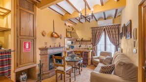 A cozy living room with a fireplace, wooden furniture, and a dining area. - Holiday Home 'Albahaca' with Mountain View, Wi-Fi and Air Conditioning (Hinojares)