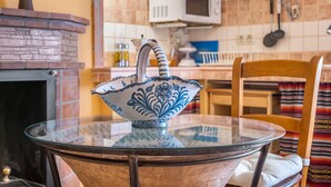 A kitchen with a microwave, a stove, and a glass table with a decorative bowl. - Holiday Home 'Albahaca' with Mountain View, Wi-Fi and Air Conditioning (Hinojares)