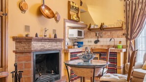 A kitchen with a brick fireplace, a microwave, and various kitchen utensils. - Holiday Home 'Albahaca' with Mountain View, Wi-Fi and Air Conditioning (Hinojares)
