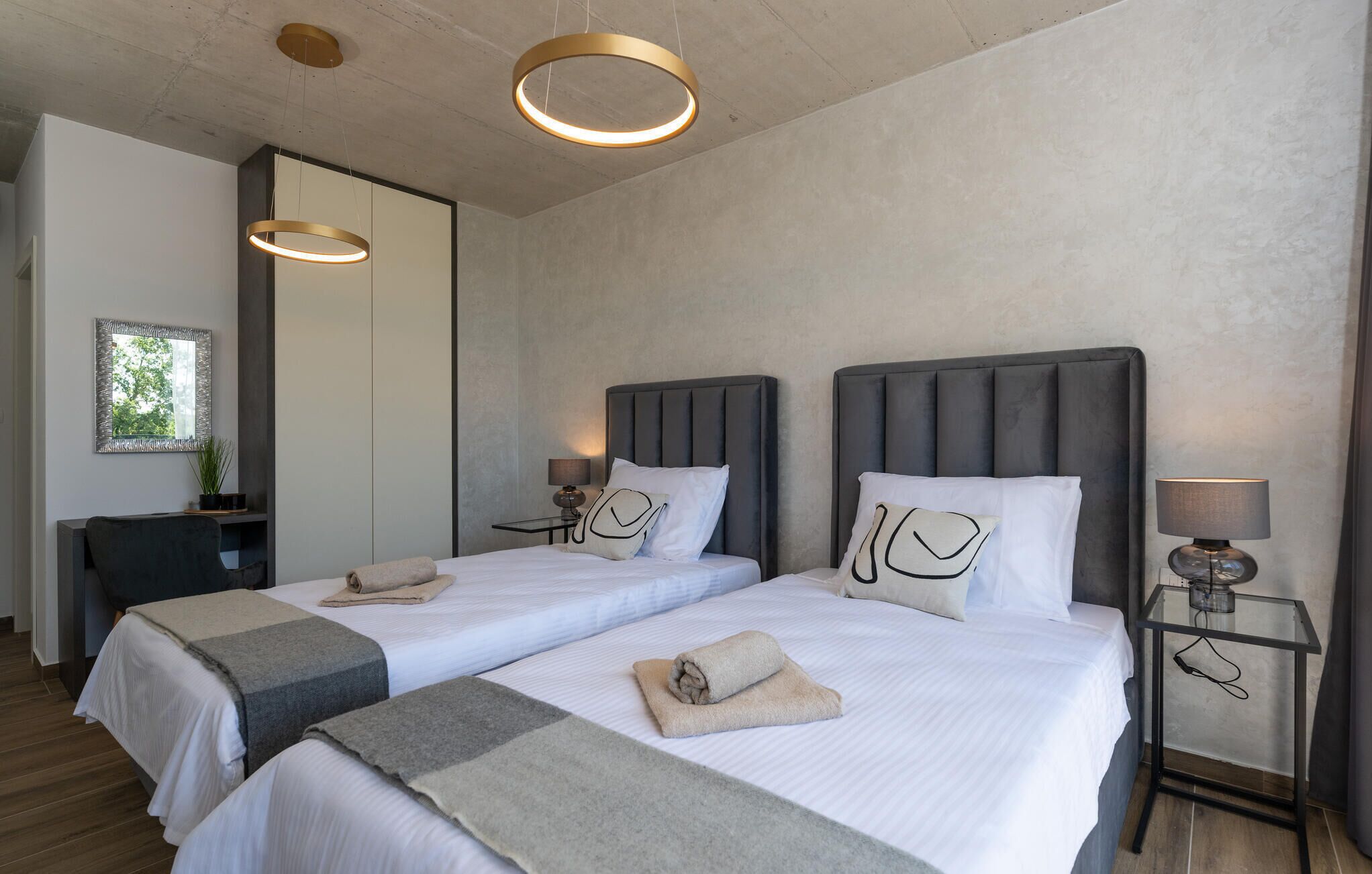 A hotel room with two beds, a desk, and a chair.
