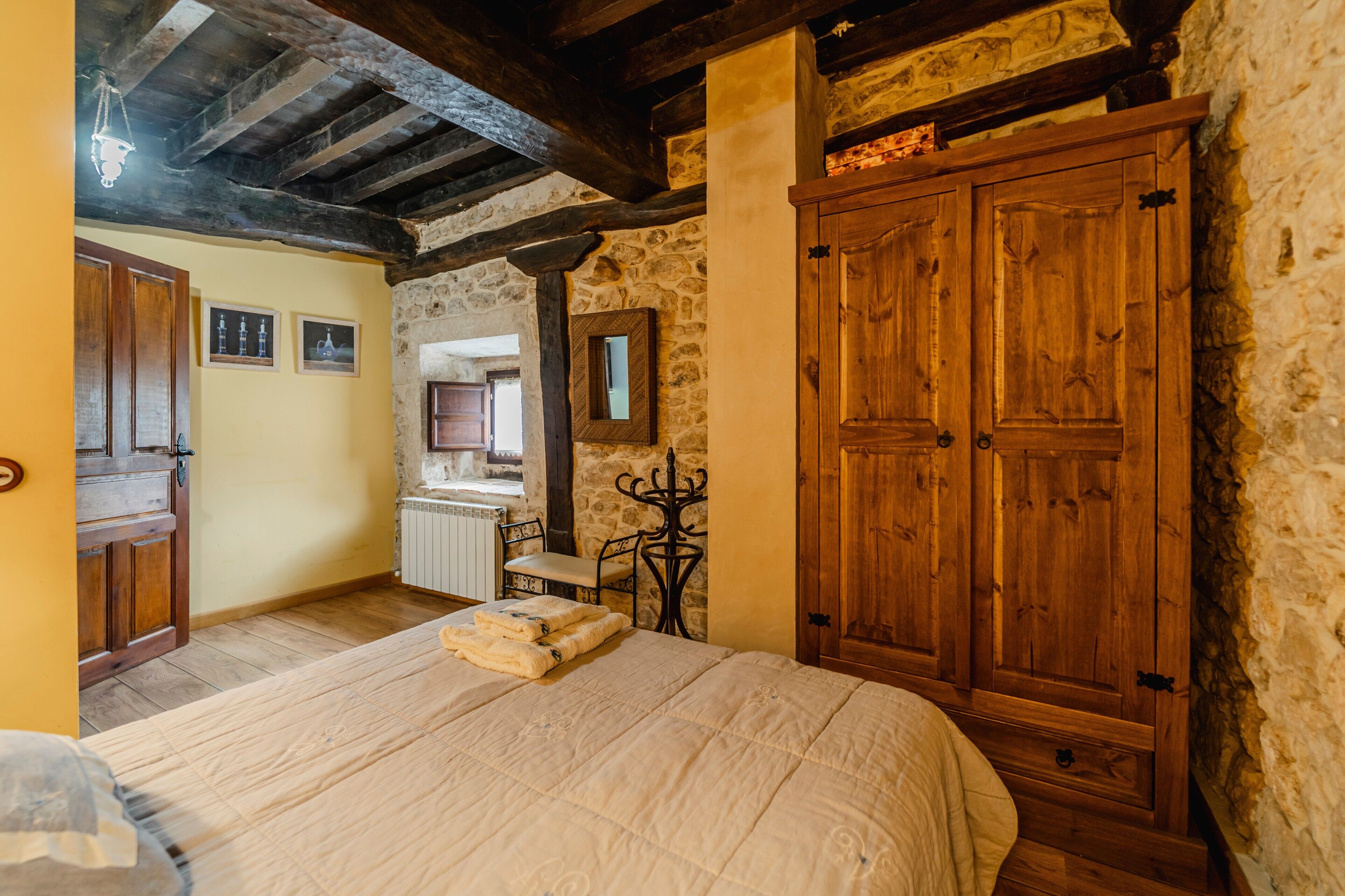 Un dormitorio con cama de madera, paredes de piedra, armario de madera y chimenea de piedra.
