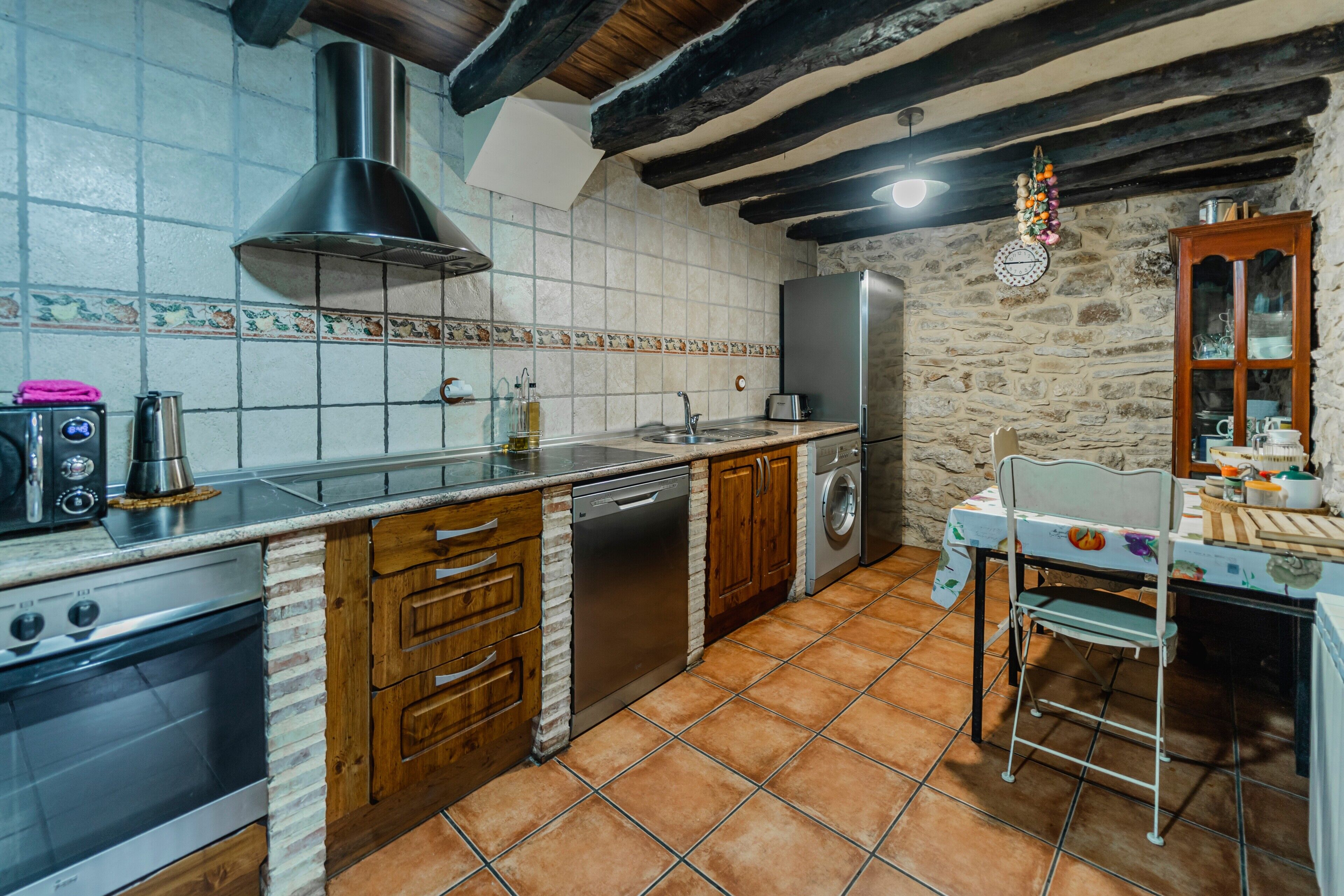 Una cocina con estufa, lavavajillas, pileta y alacenas de madera.