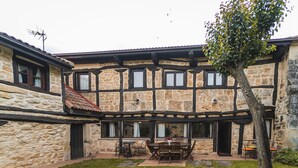 A stone building with a courtyard, a dining table, and chairs.